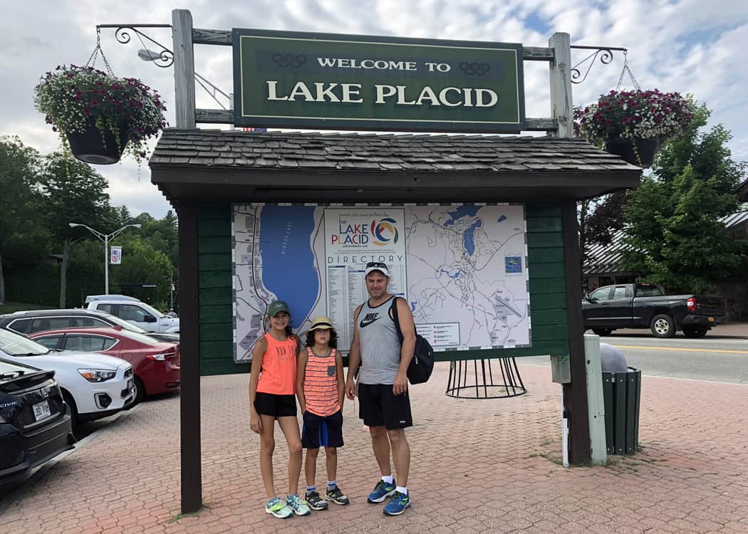 Lake-Placid-in-Summer-Family-in-front-of-Lake-Placid-sign